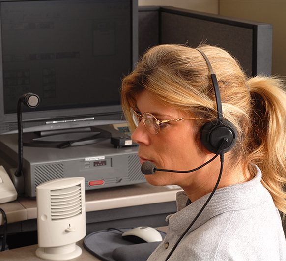 a woman sits at her desk in an office while wearing a headset