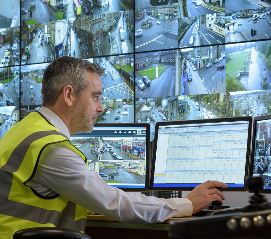 Man in front of wall of security camera feeds