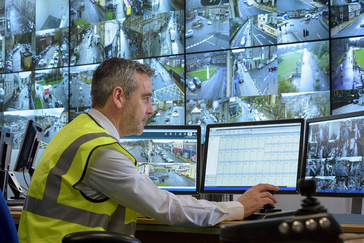 Man in front of wall of security camera feeds